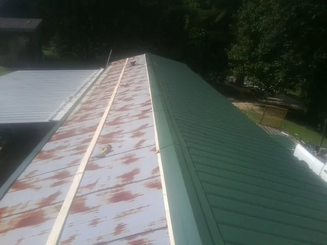 Old rusted panels beside newly installed green metal roofing — Wind Damage Roof Repair by Roofing Brothers in Mount Olive